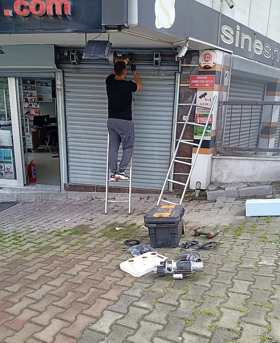 Merdiven üzerinde kepenk motoru servisi yapan usta